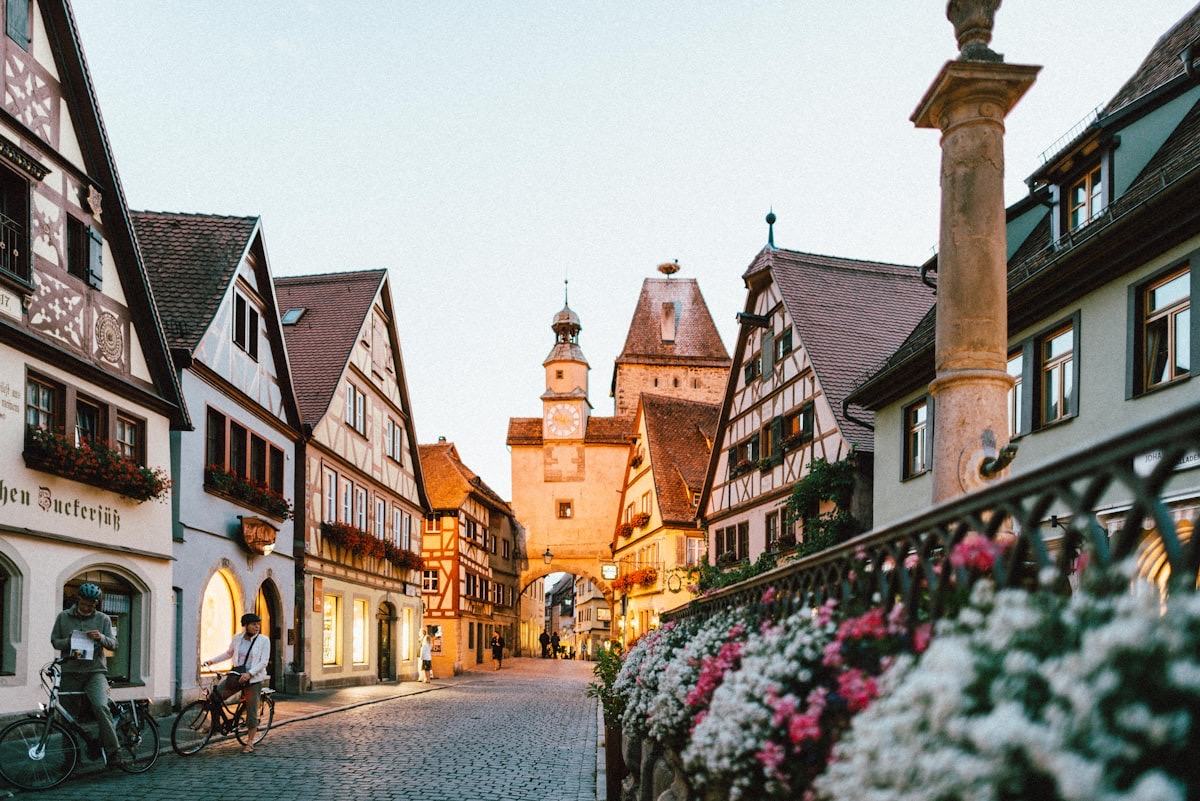 Zwei Radfahrer in einer Altstadtgasse mit Fachwerkhäusern und Blumen