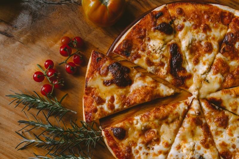 Aufgeschnittene Pizza auf einem Holzbrett zum Teilen