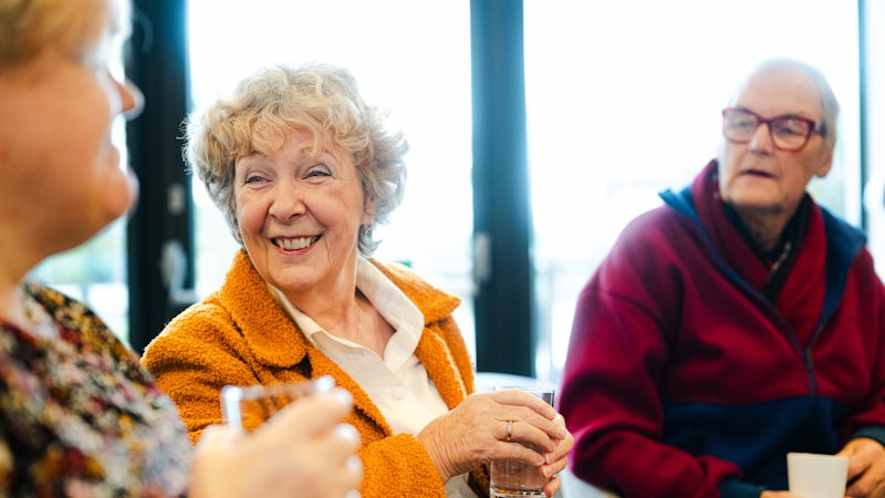 Drei ältere Freunde lachen zusammen an einem Tisch