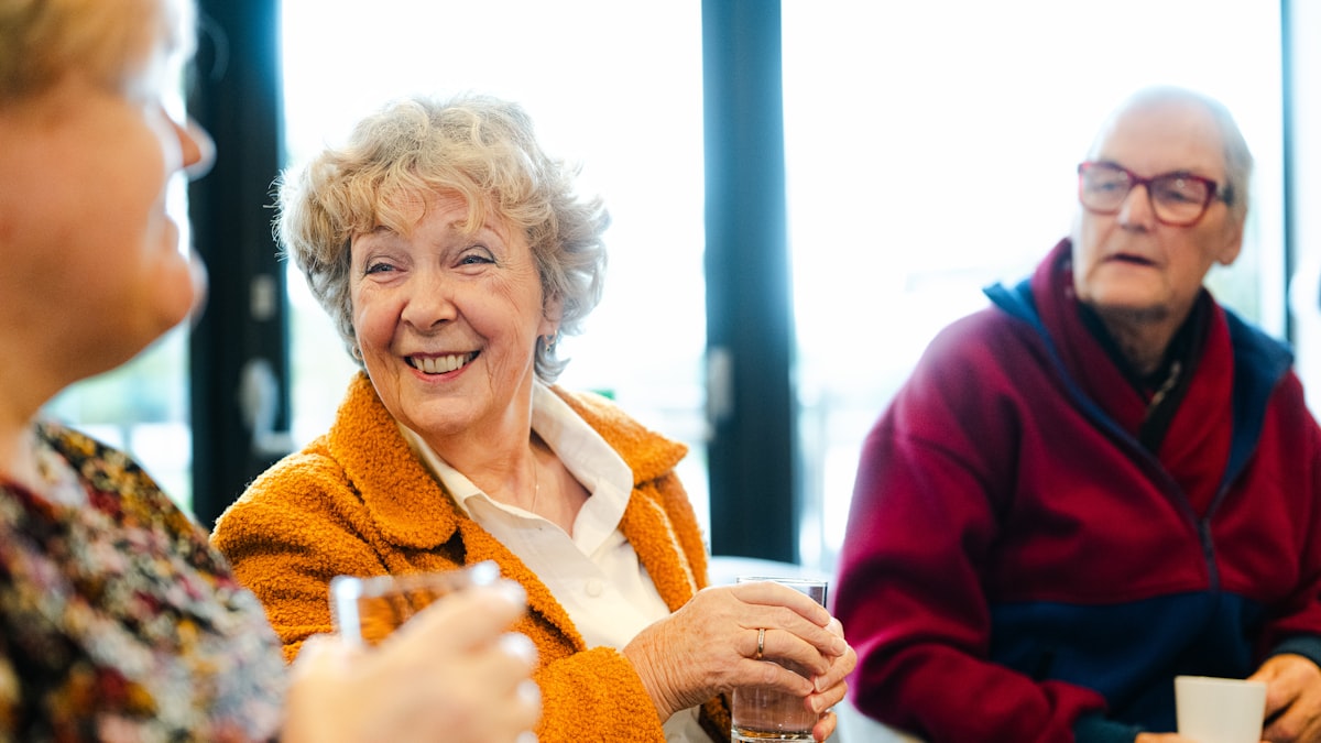 Drei ältere Freunde lachen zusammen an einem Tisch